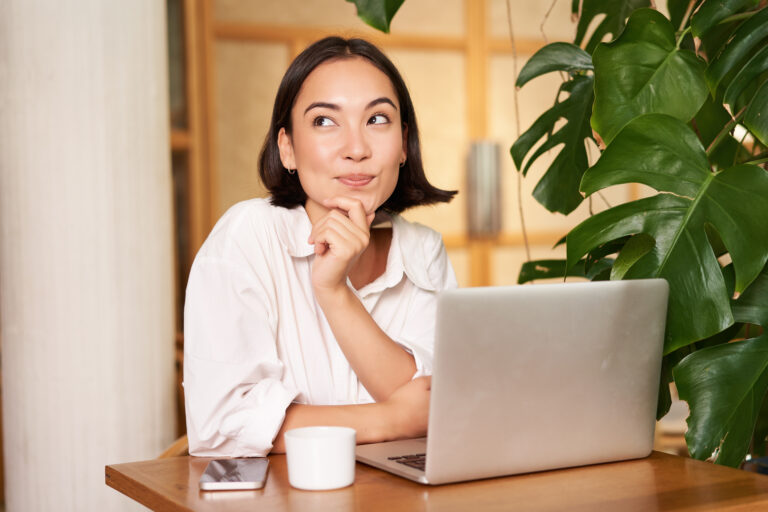 Confident young stylish woman with laptop, sitting in cafe and working, freelancer in co-working space with cup of coffee.